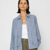 Person wearing a blue striped shirt over a white top and green pants on a white background