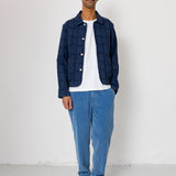 Man wearing a blue jacket, white shirt, and blue jeans standing against a white background