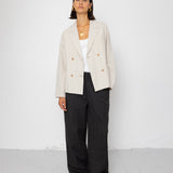 Person wearing a beige blazer and black pants against a white background