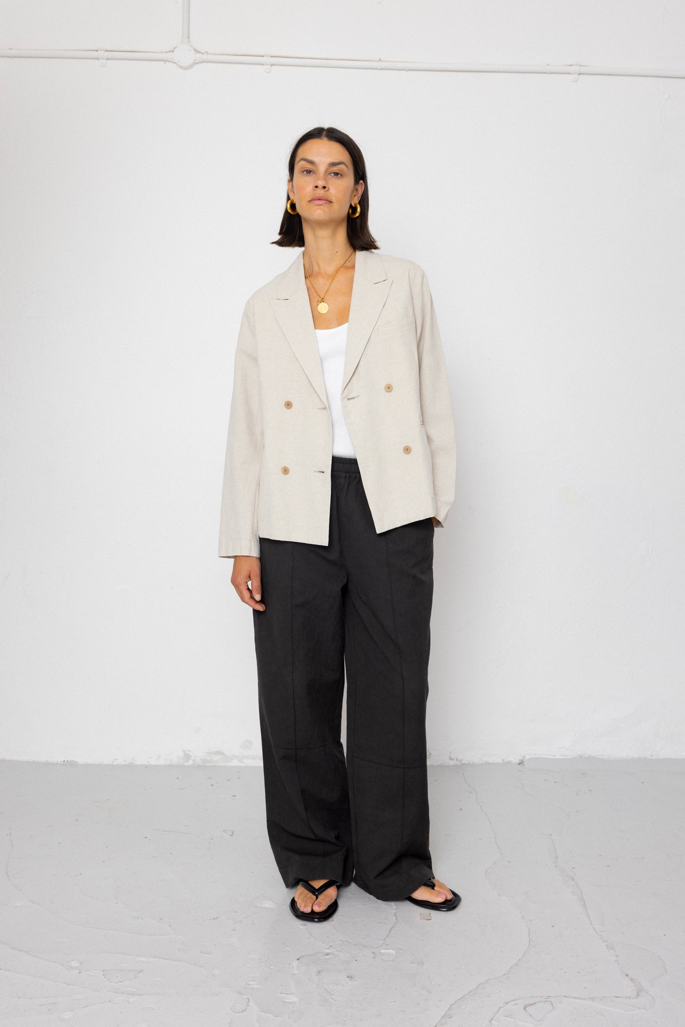 Person wearing a beige blazer and black pants against a white background