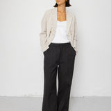 Woman wearing a beige blazer, white top, and black pants against a white background