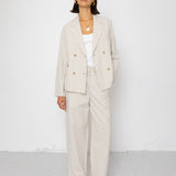 Woman wearing a beige suit with a white top on a white background