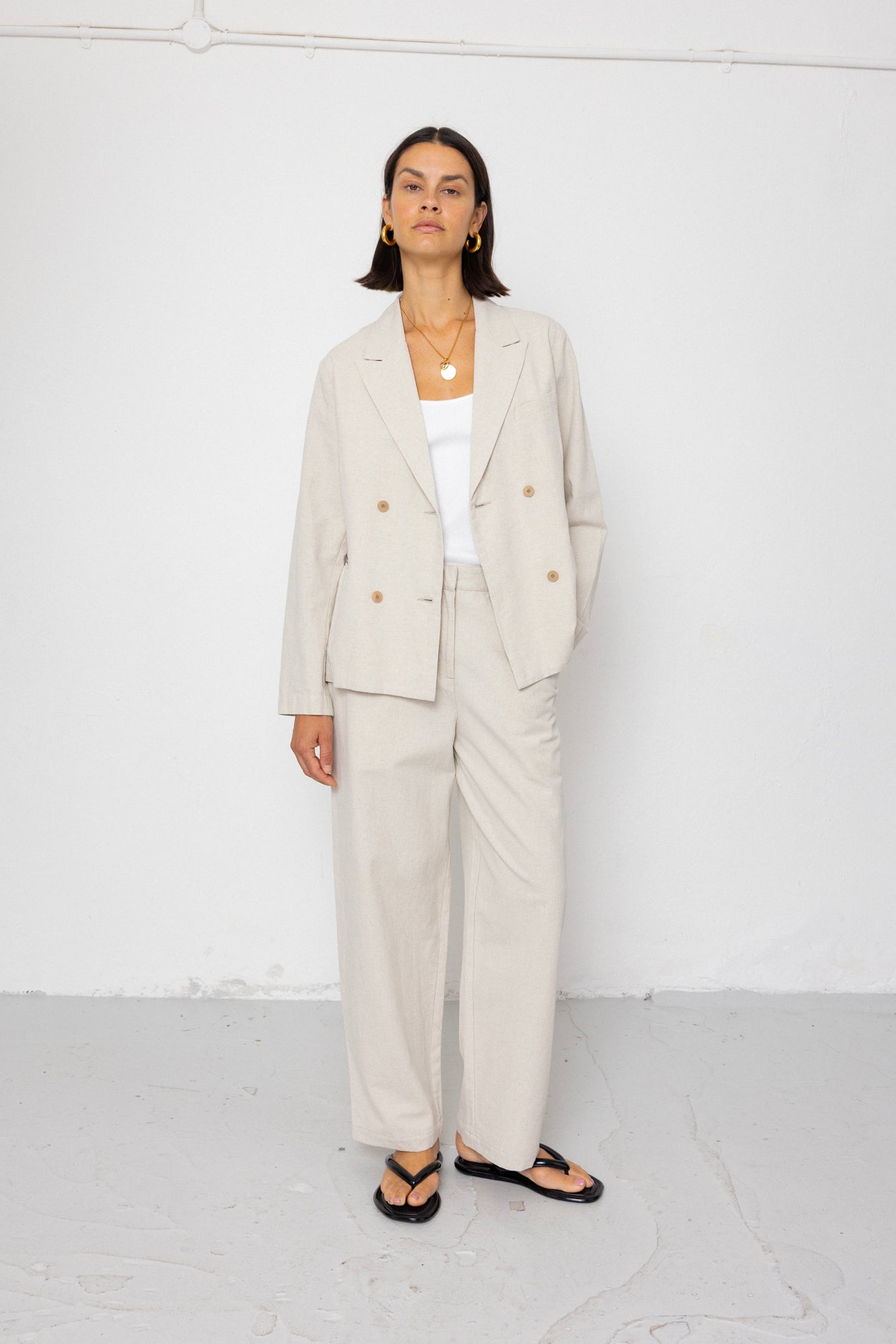 Woman wearing a beige suit with a white top on a white background
