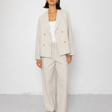 Woman wearing a beige suit with a white top against a white background