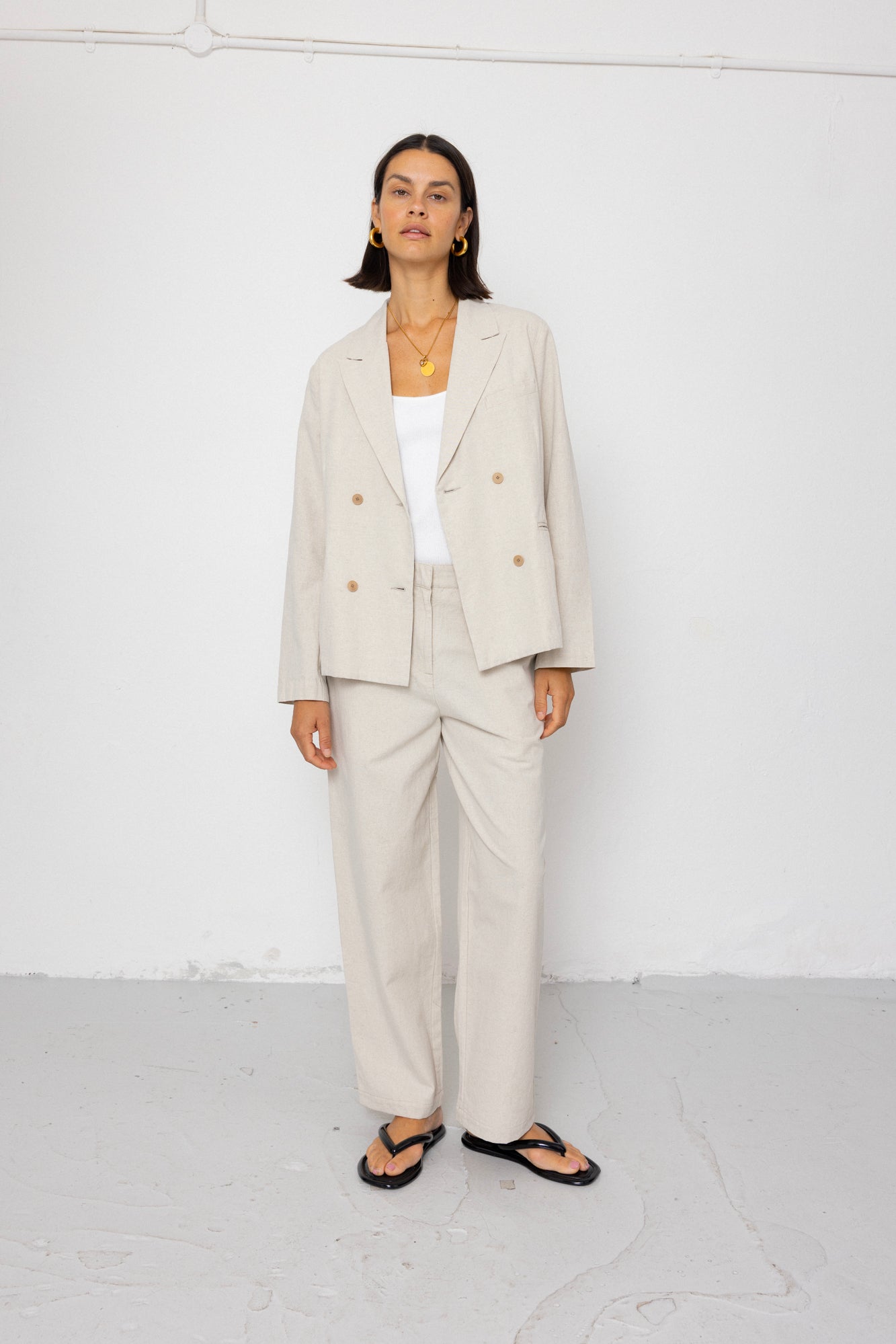 Woman wearing a beige suit with a white top against a white background