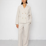 Woman wearing a beige suit standing against a white background