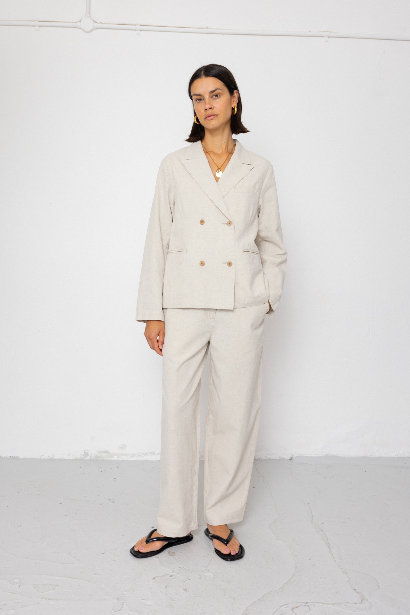 Woman wearing a beige suit standing against a white background