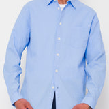 Man wearing a light blue button-up shirt against a white background