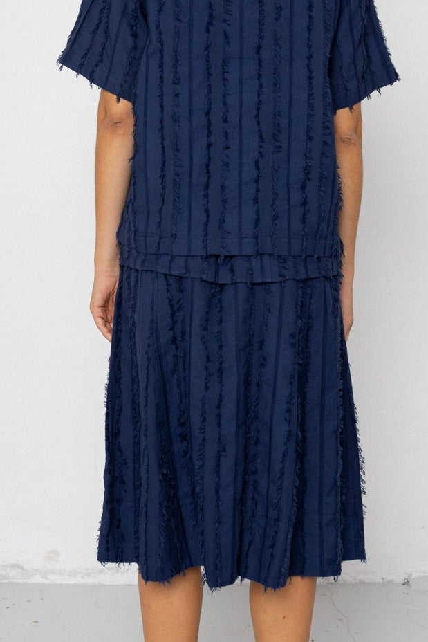 Person wearing a navy blue textured outfit against a white background