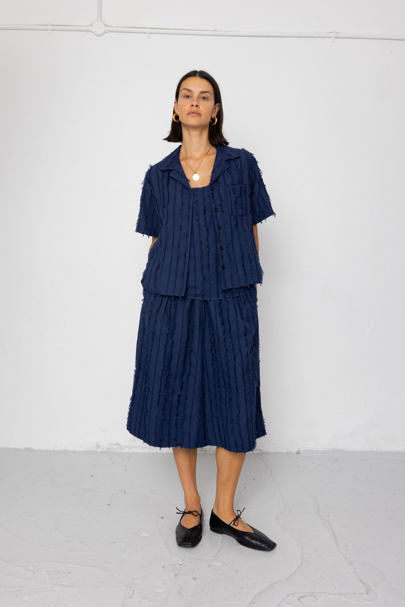 Woman wearing a navy blue shirt and textured skirt against a white background