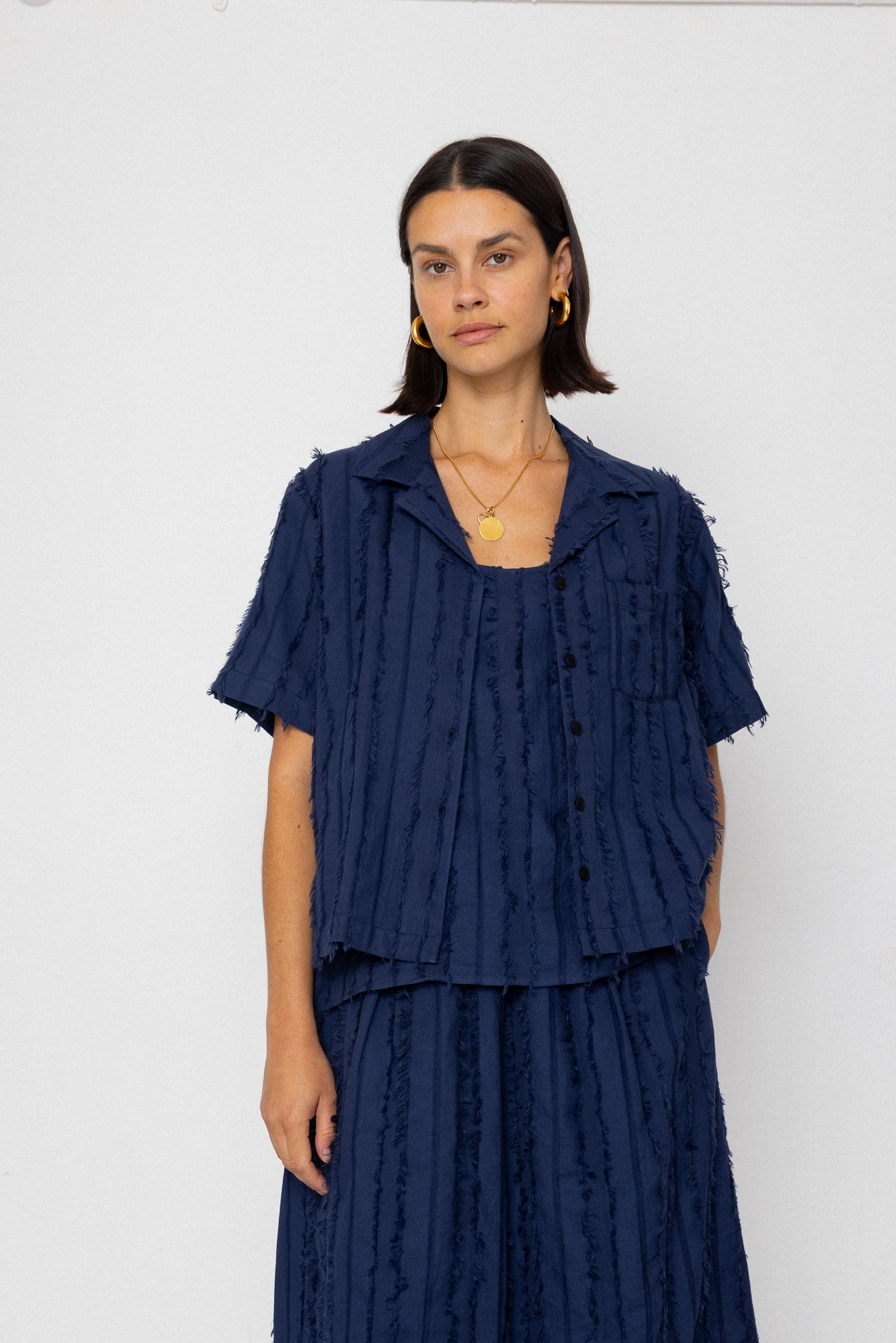 Woman wearing a navy blue textured outfit against a white background