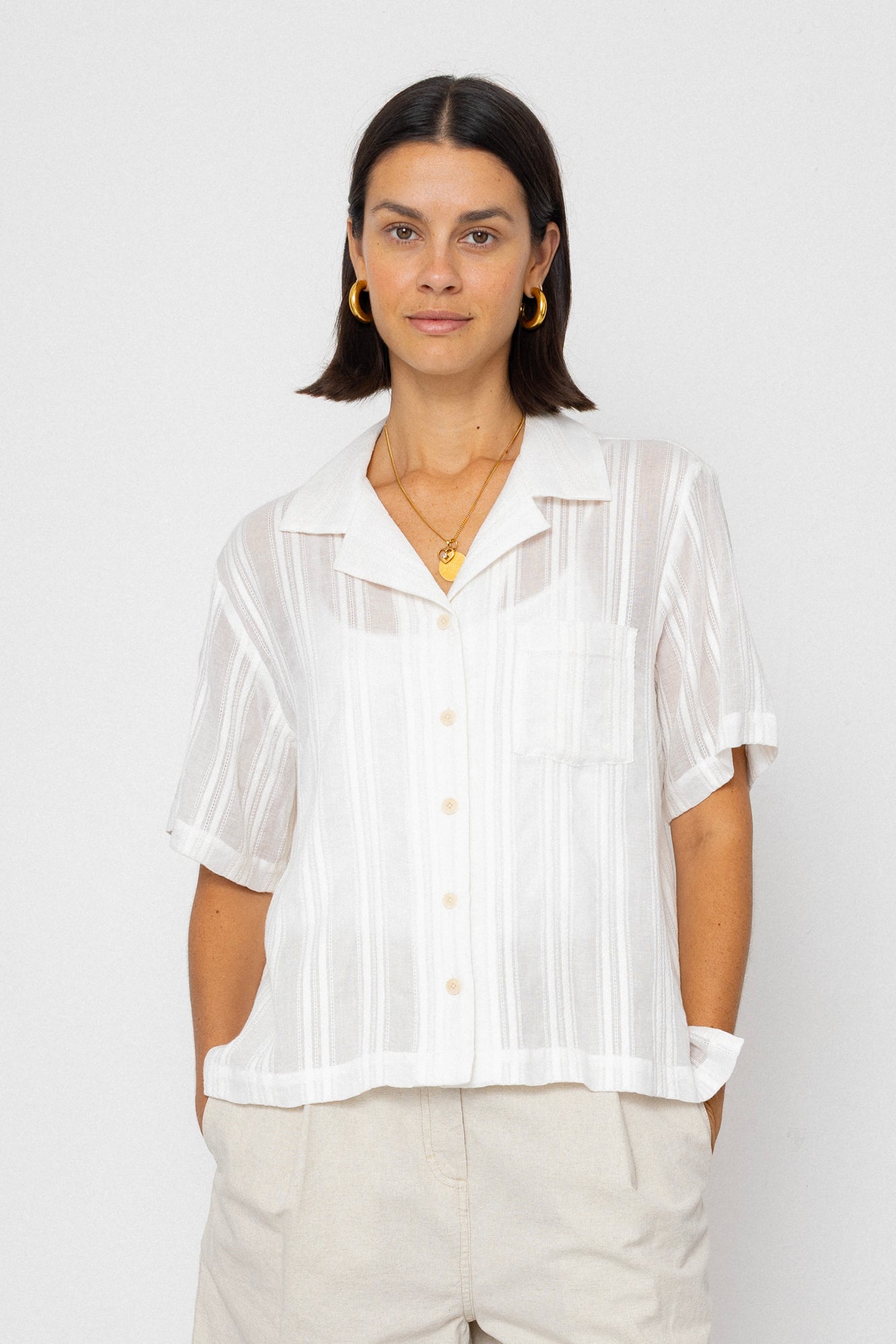 Woman wearing a white blouse with sheer sleeves against a plain background