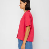 Person wearing a red shirt and blue shorts against a white background