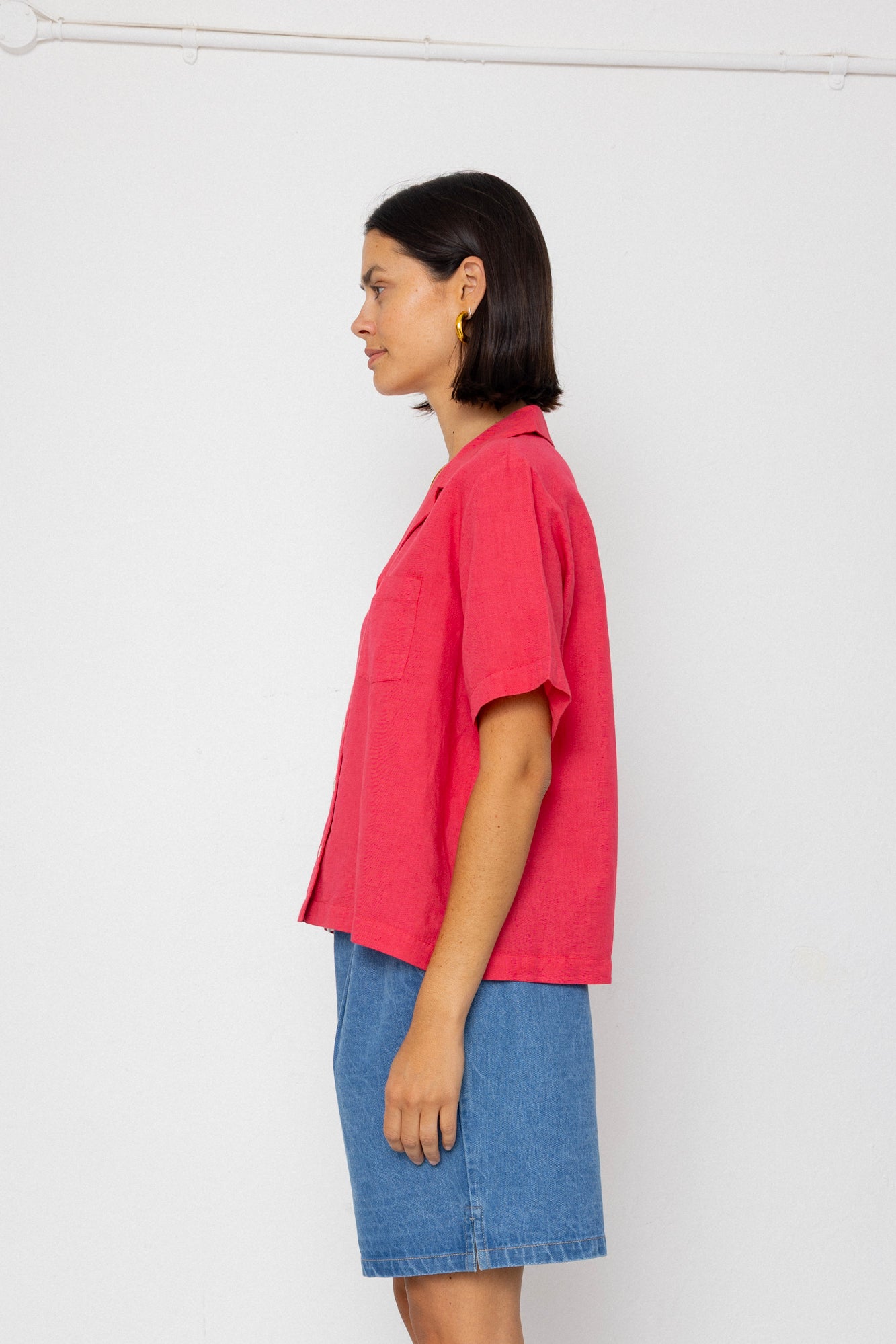 Person wearing a red shirt and blue shorts against a white background