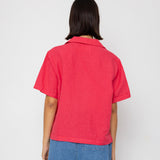 Person wearing a red shirt and blue shorts against a white background
