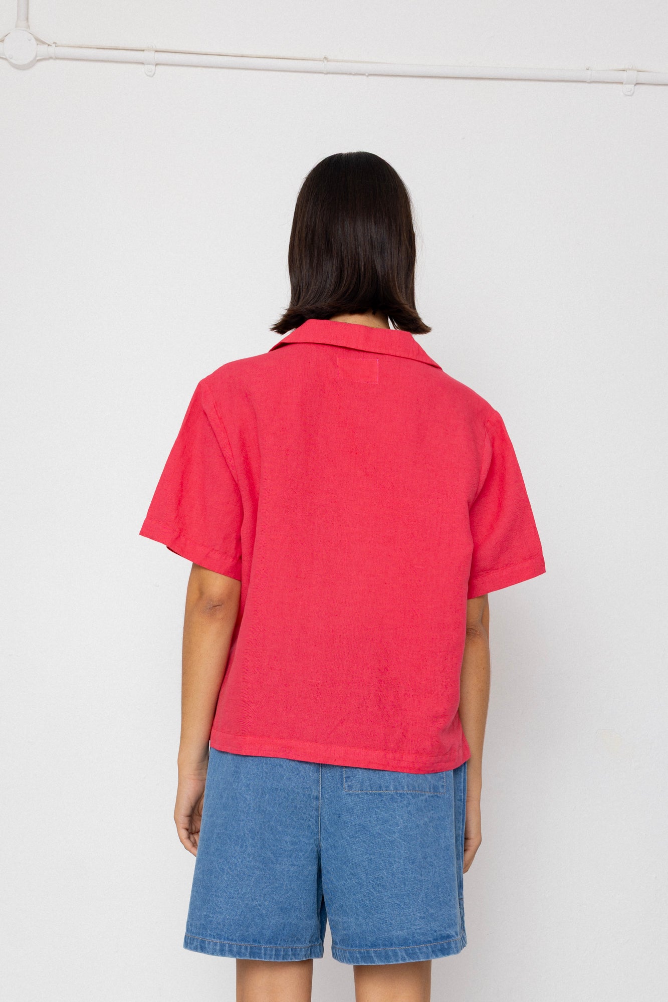 Person wearing a red shirt and blue shorts against a white background