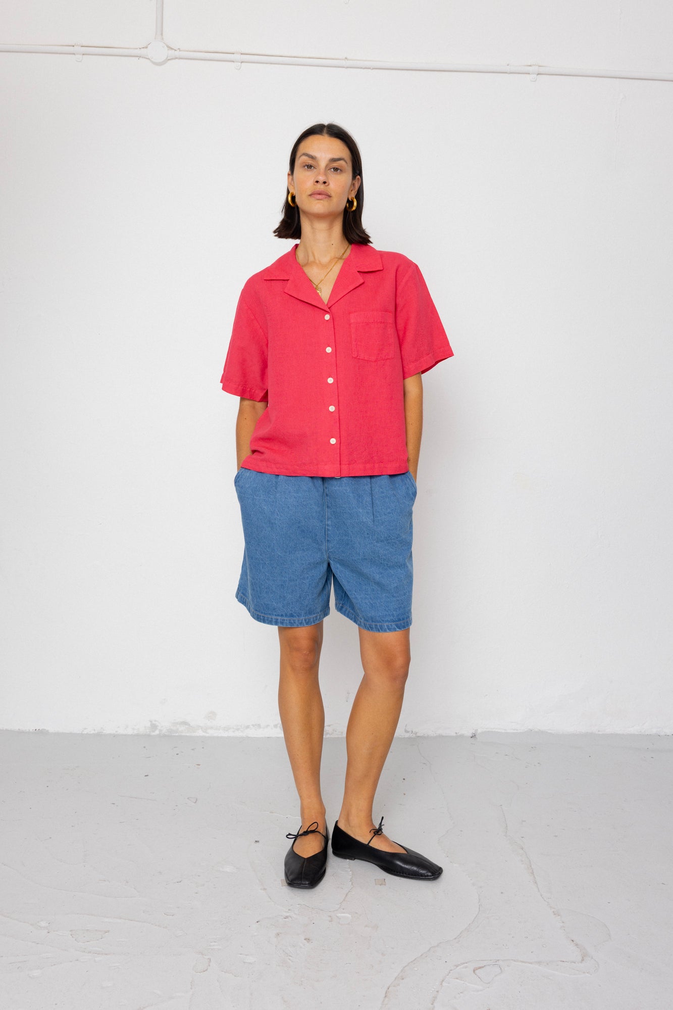 Person wearing a red shirt and blue shorts against a white background
