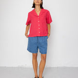Person wearing a pink shirt and blue shorts against a white background