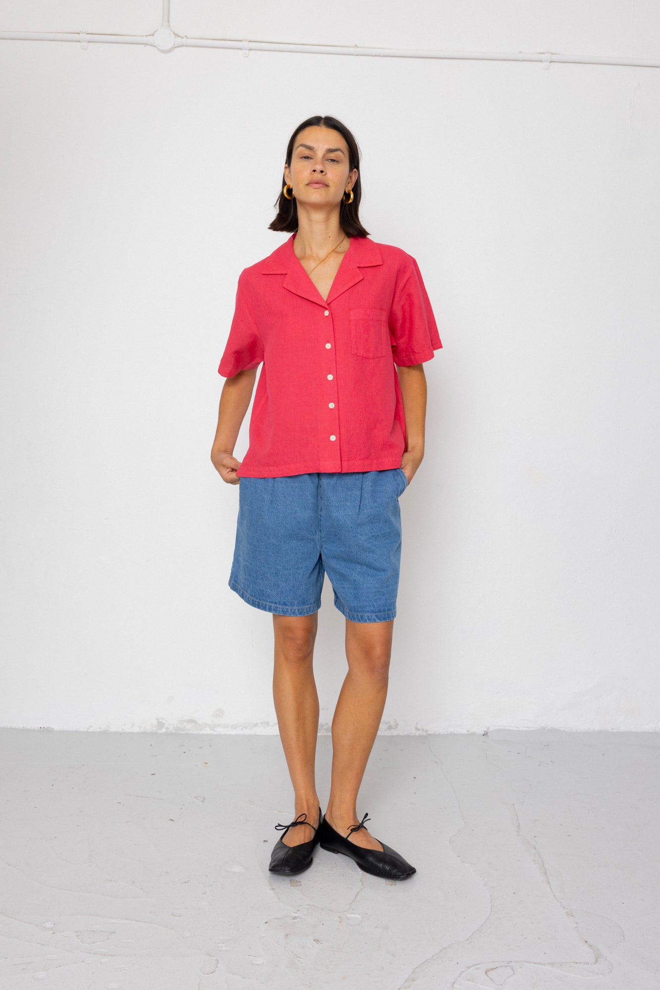 Person wearing a pink shirt and blue shorts against a white background
