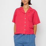 Woman wearing a red shirt and blue shorts against a white background