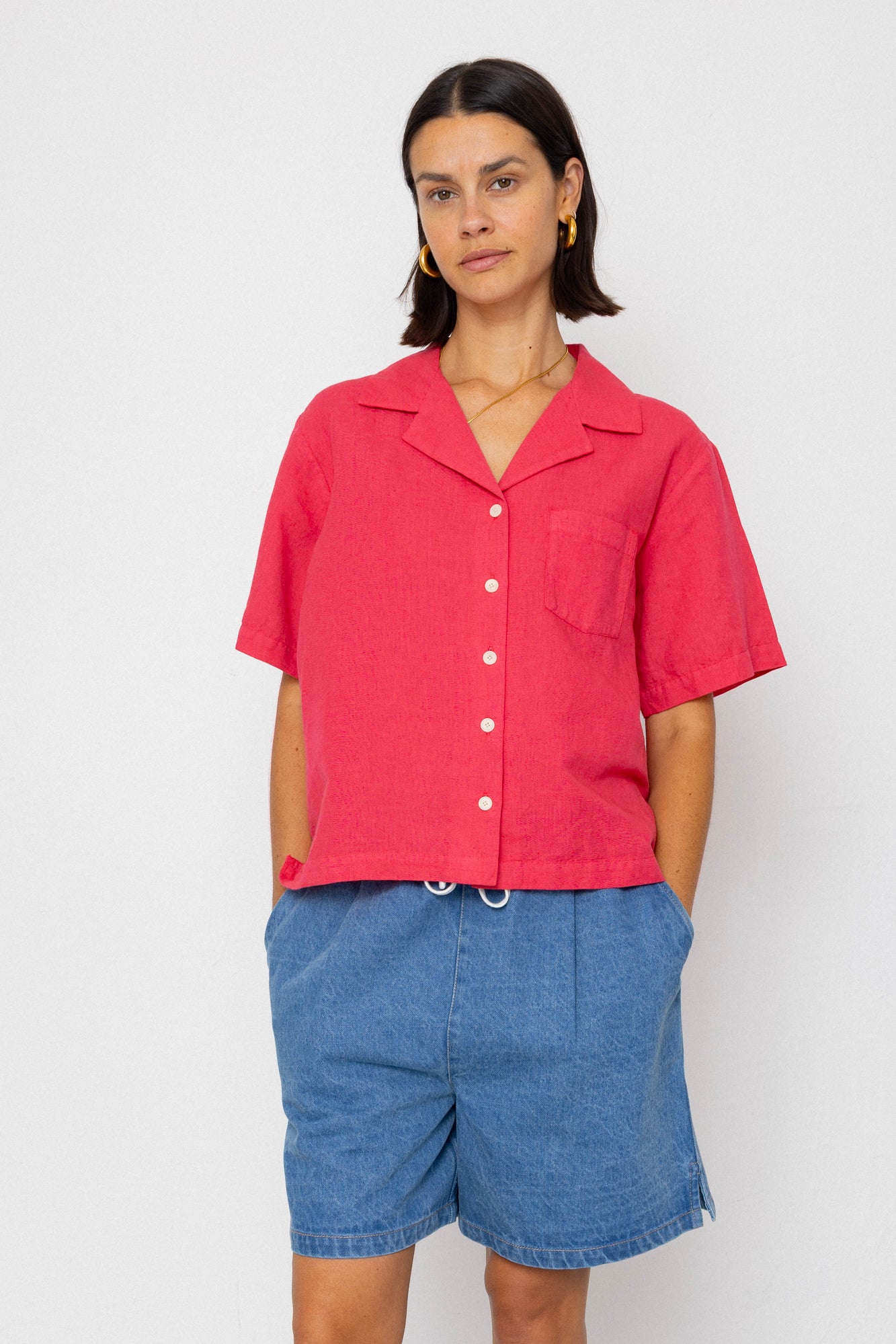 Woman wearing a red shirt and blue shorts against a white background