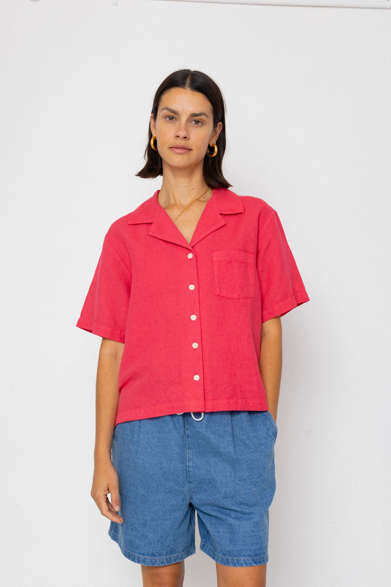 Person wearing a red shirt and blue shorts on a white background