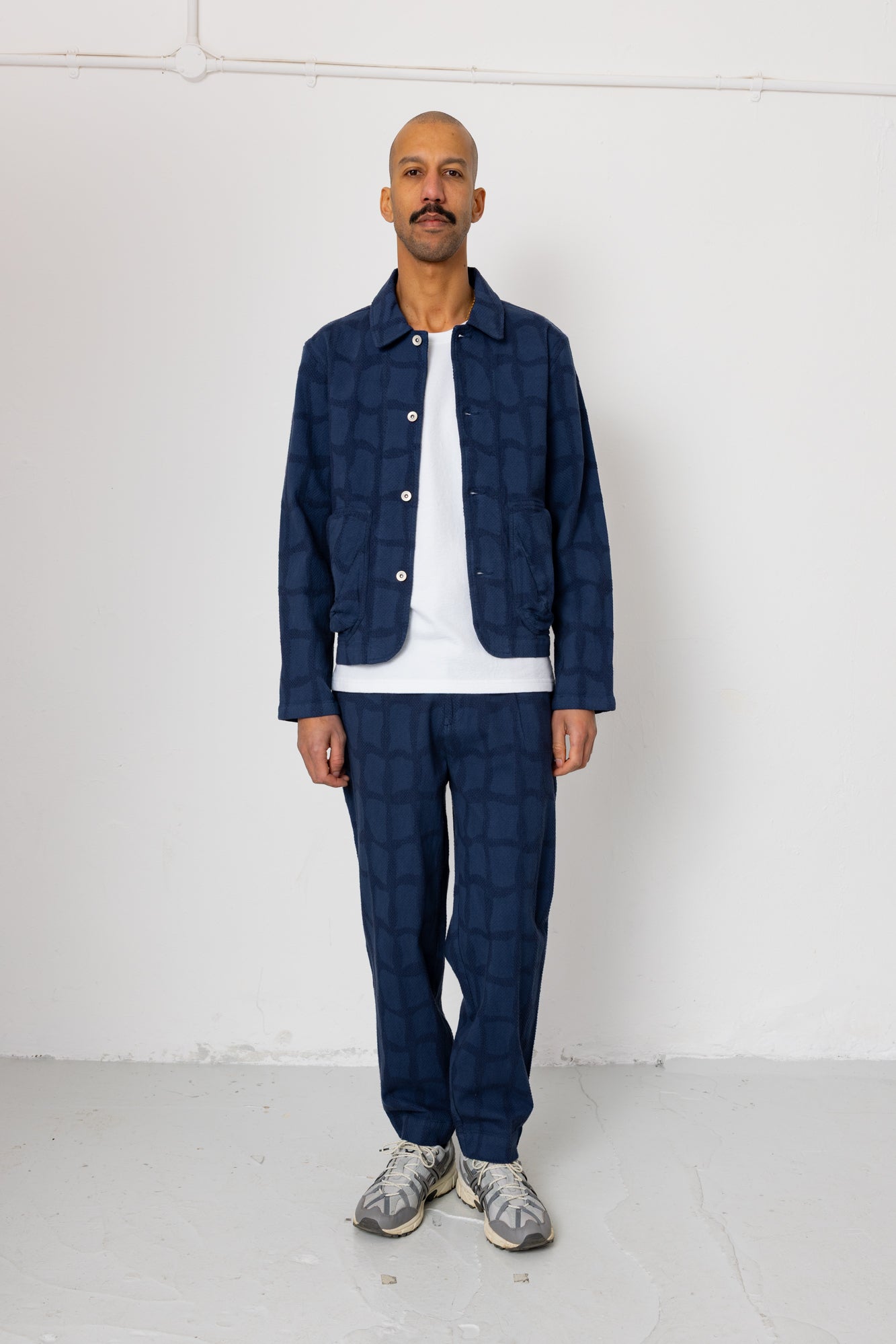 Man wearing a blue checkered outfit against a white background