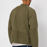Person wearing an olive green jacket on a white background
