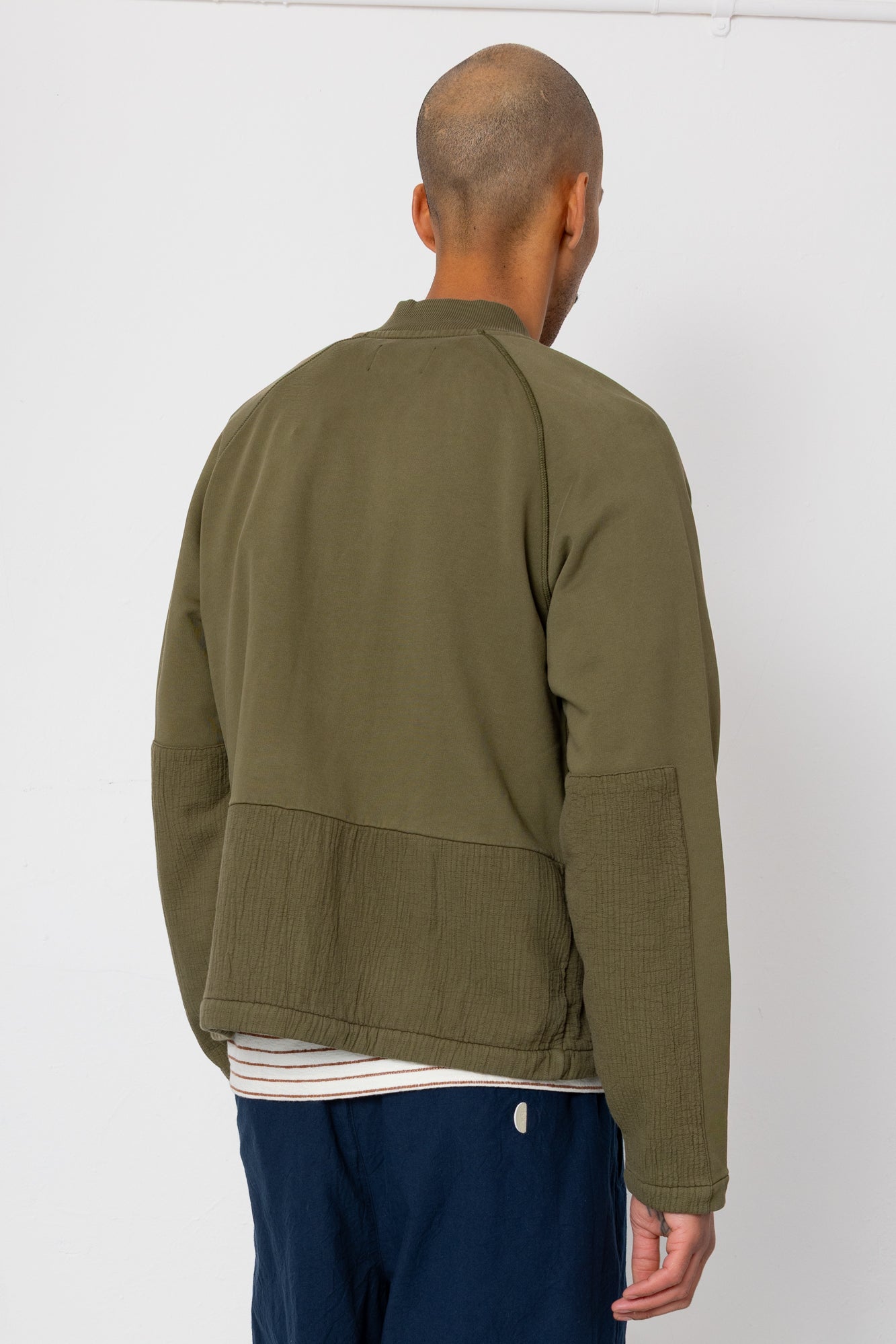 Person wearing an olive green jacket on a white background