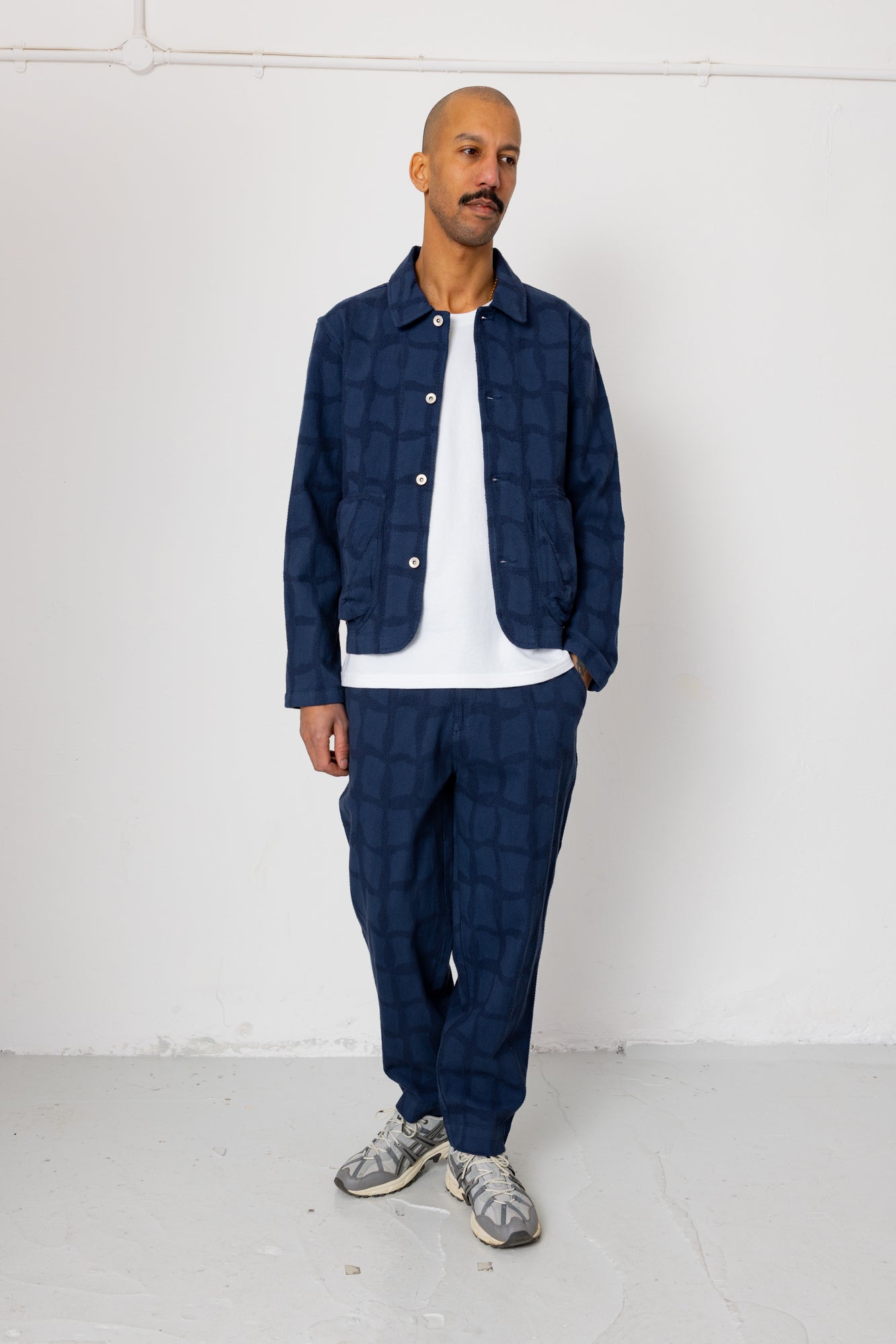 Man wearing a navy quilted jacket and pants against a white background