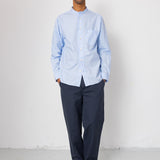 Man wearing a light blue shirt and dark pants against a white background