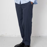 Person wearing a light blue shirt, dark pants, and black shoes on a white background
