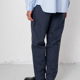 Person wearing a light blue shirt, navy pants, and black shoes on a white background