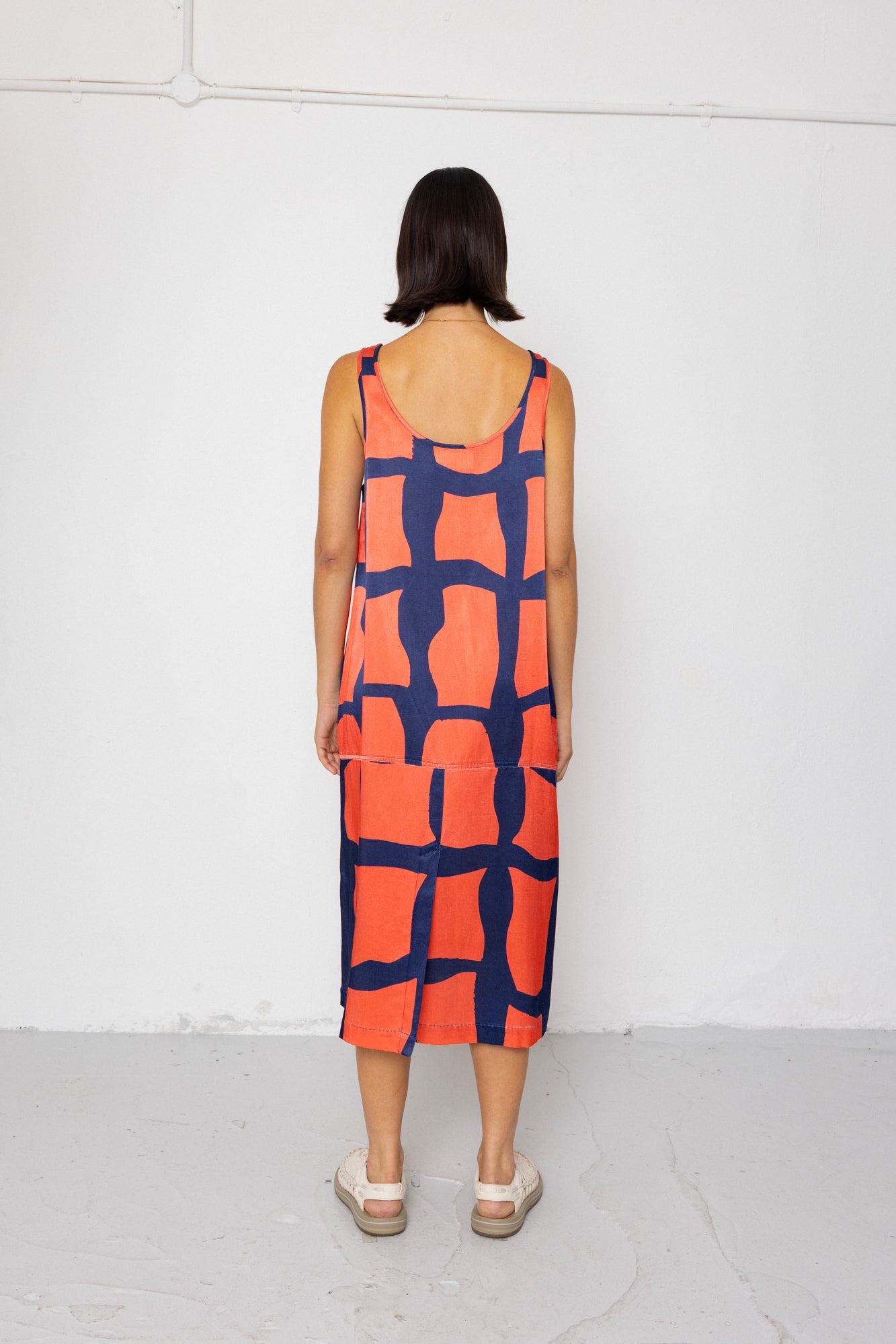 Person wearing a sleeveless dress with a geometric pattern on a white background