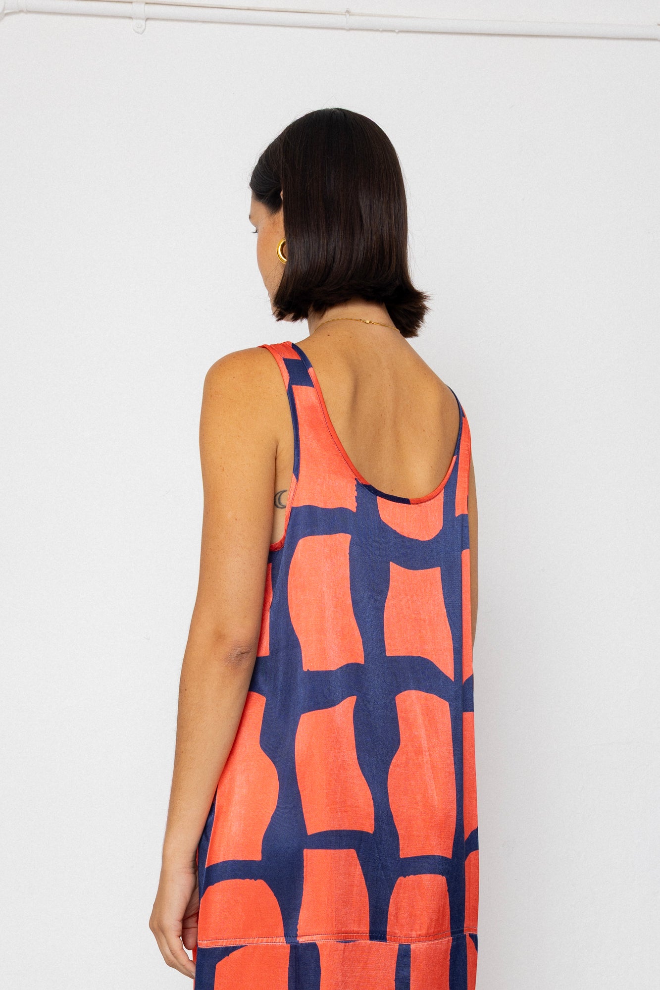 Woman wearing a sleeveless dress with a geometric pattern on a white background