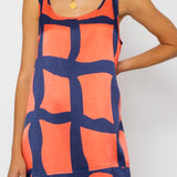 Woman wearing a sleeveless dress with a geometric pattern on a plain background
