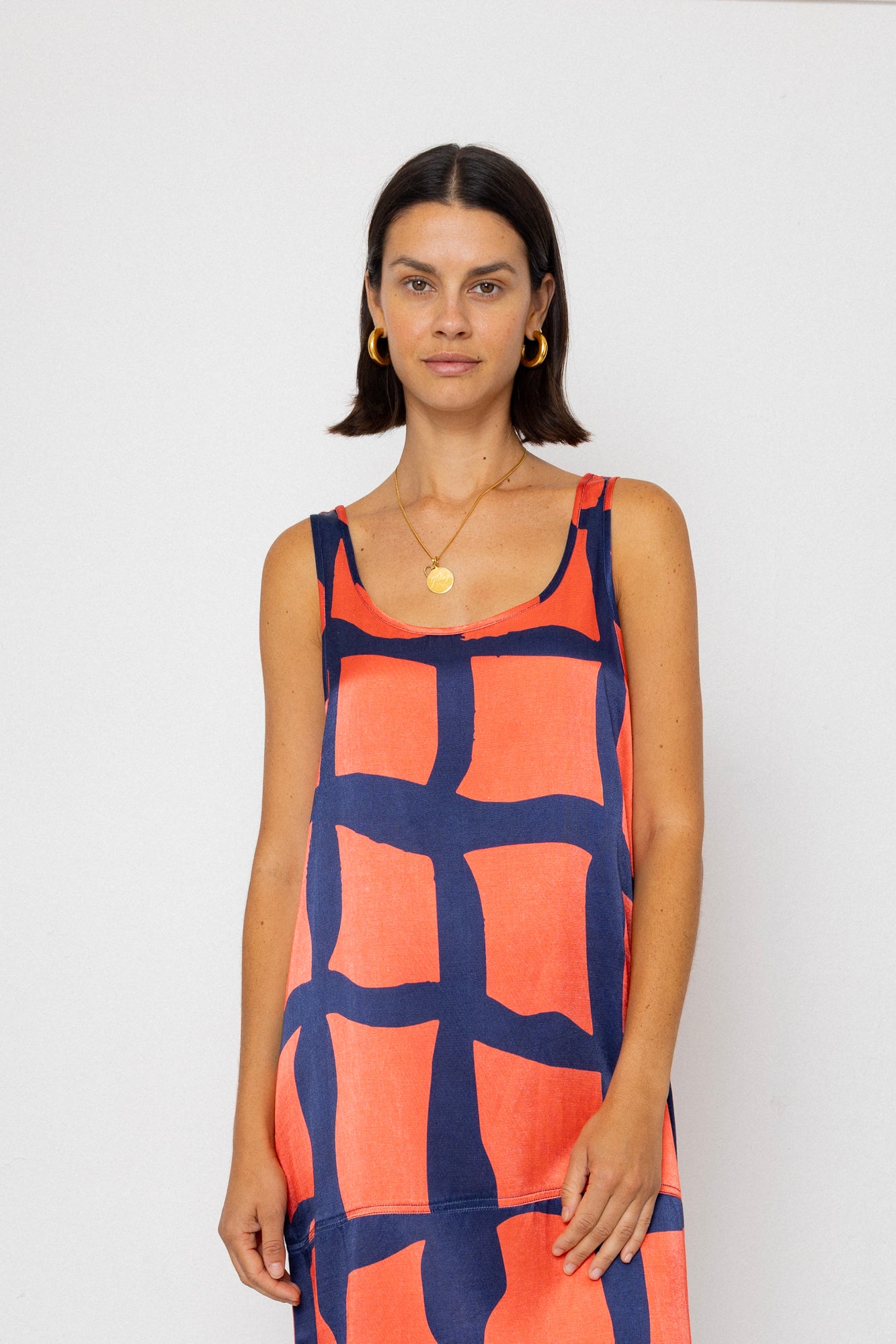 Woman wearing a sleeveless dress with a geometric pattern on a white background