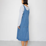 Person wearing a blue denim dress over a striped shirt against a white background