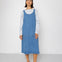 Person wearing a blue denim dress over a striped shirt on a white background