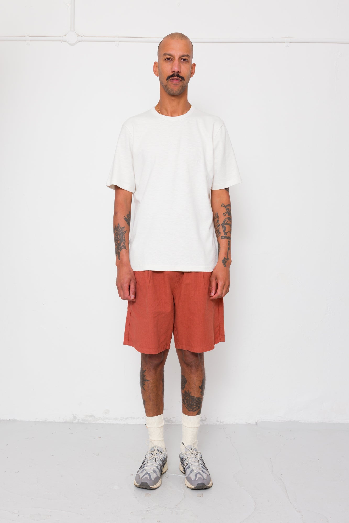 Man wearing a white t-shirt and orange shorts against a white background