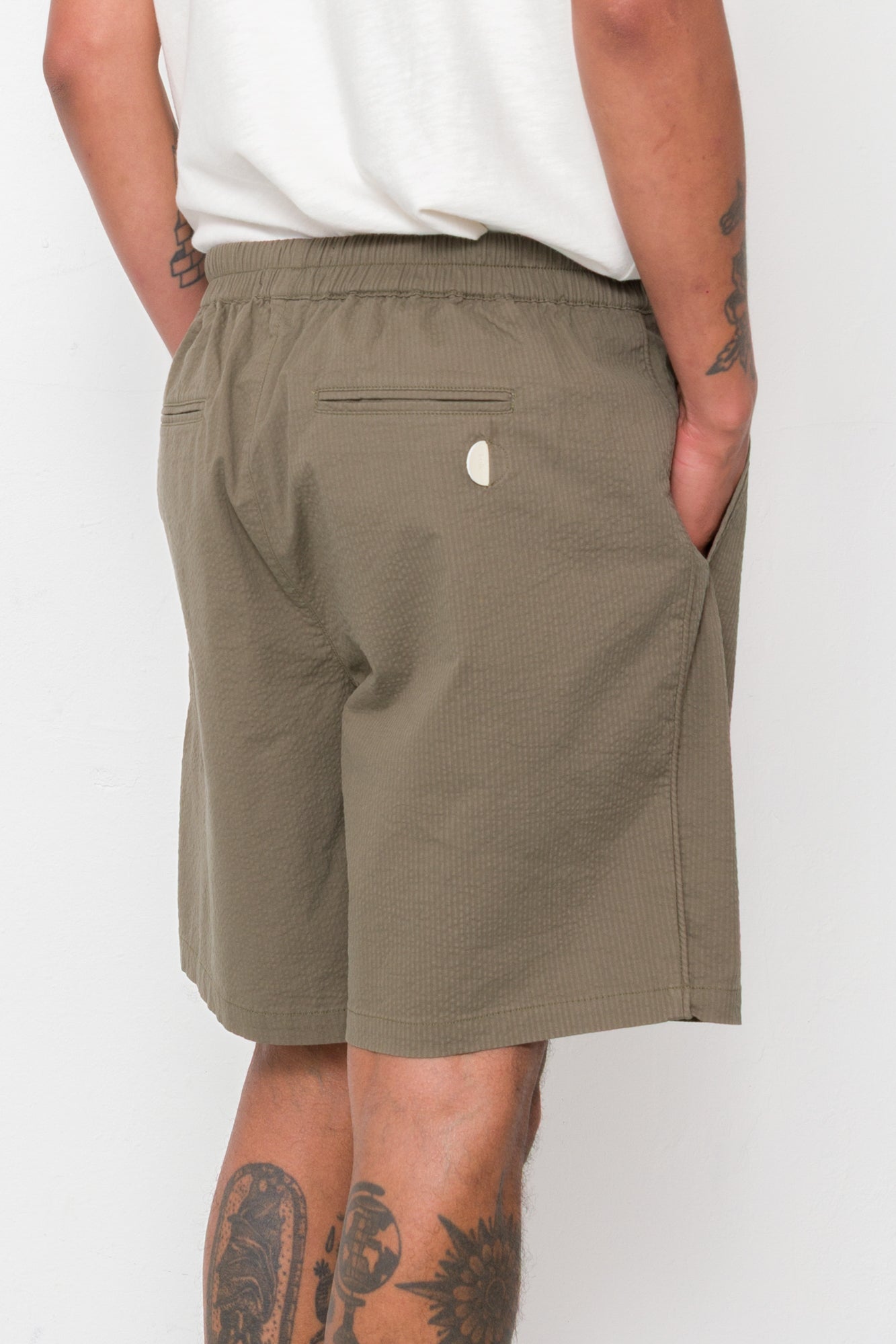 Person wearing olive green shorts on a white background