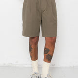 Person wearing olive green shorts and gray sneakers on a white background