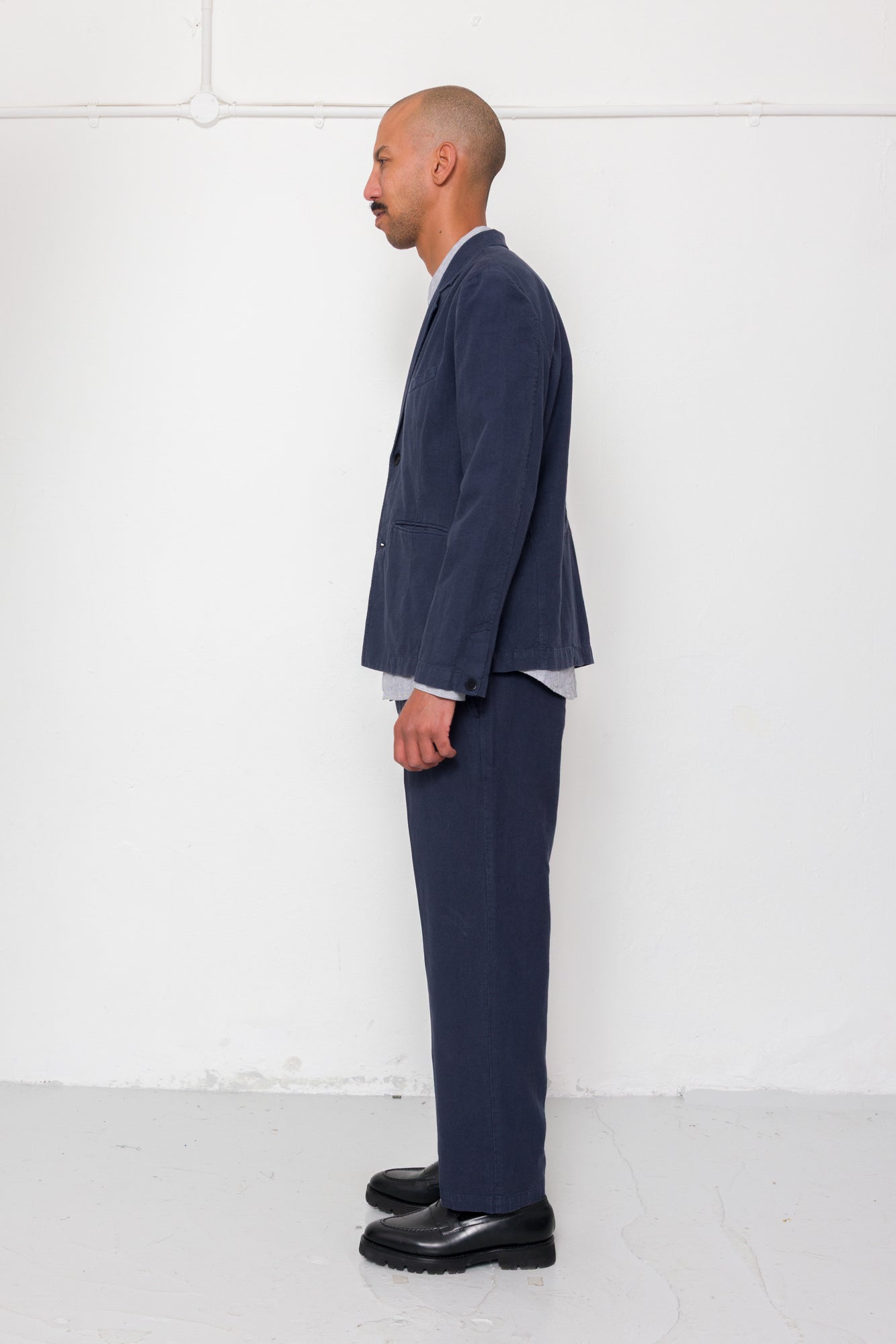 Man wearing a navy suit with a white shirt against a white background