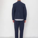 Person wearing a navy suit standing against a white wall