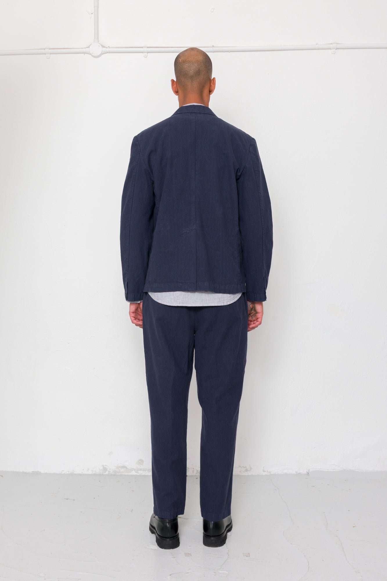 Person wearing a navy suit standing against a white wall