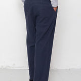 Person wearing navy pants and black shoes against a white background