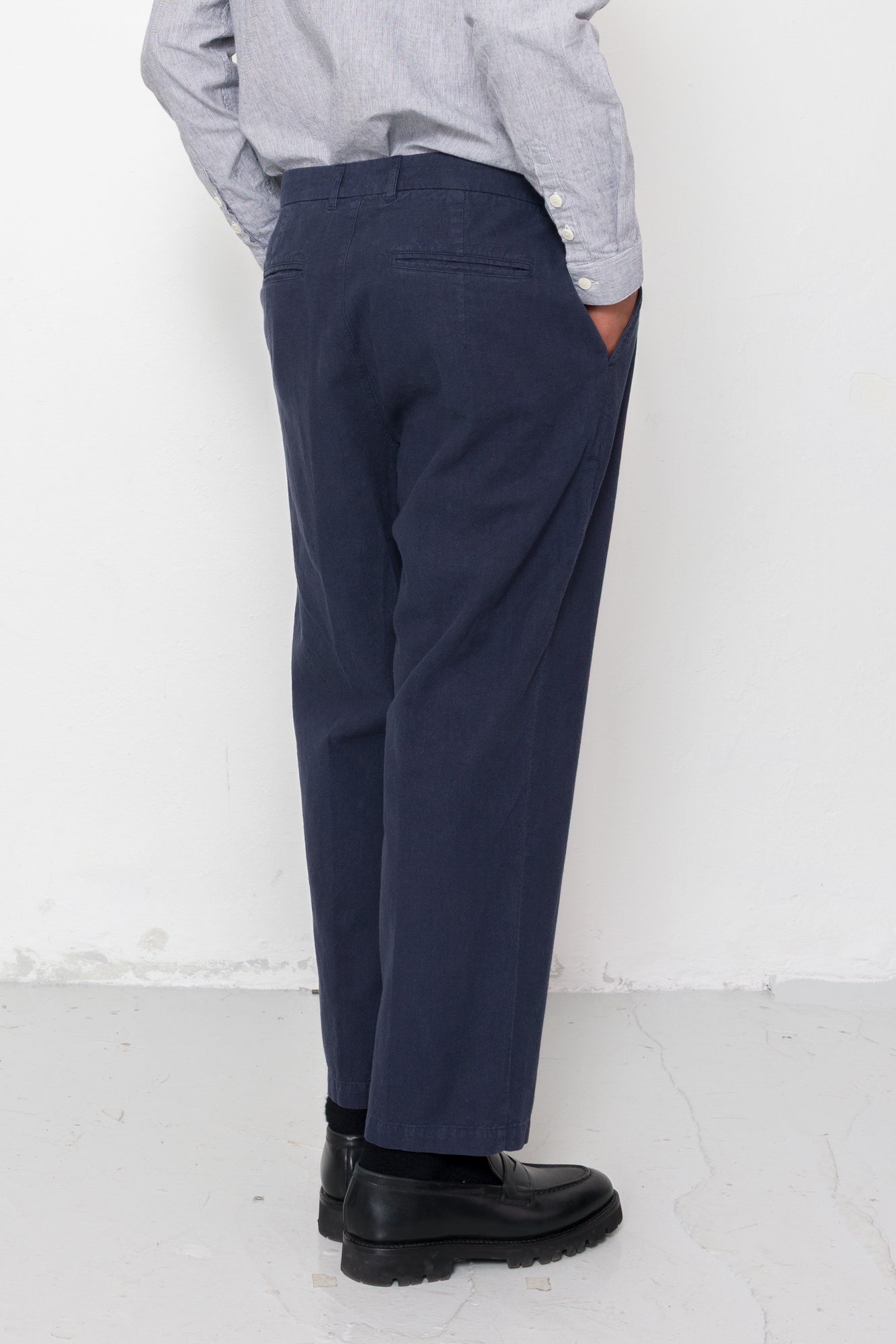 Person wearing navy pants and black shoes against a white background