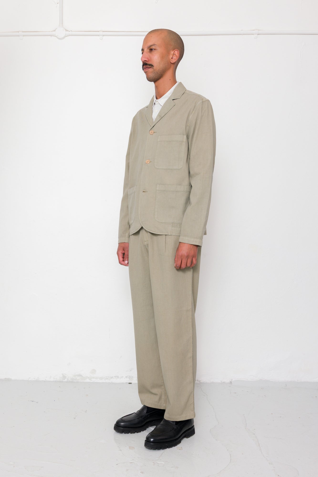 Man wearing a beige suit standing against a white background