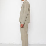 Man wearing a beige suit standing against a white background