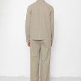 Person wearing a beige suit standing against a white background